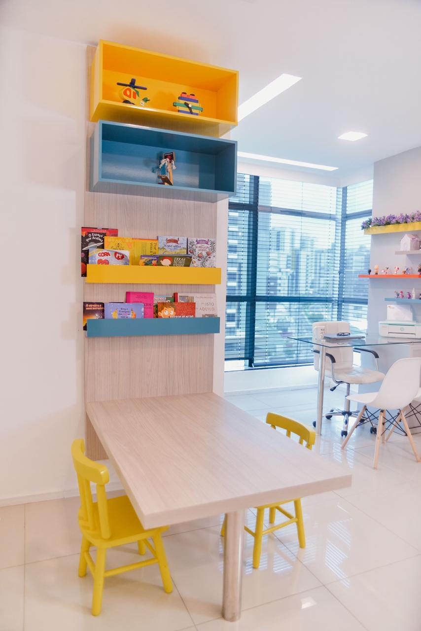 Espaço de atendimento infantil com mesa, brinquedos e materiais terapêuticos